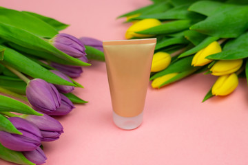 A gold tube placed on pink paper at the flowers. Ideal banner with a space for copy.