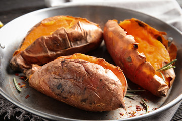 Dish with baked sweet potatoes on table, closeup