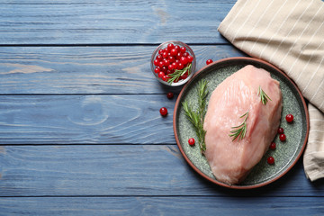 Plate with raw turkey fillet and ingredients on wooden background, top view. Space for text