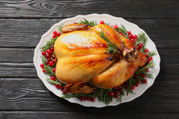 Platter of cooked turkey with garnish on wooden background, top view