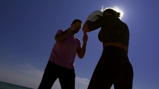 man is training woman of self-defense techniques in nature, she is performing punches by hands