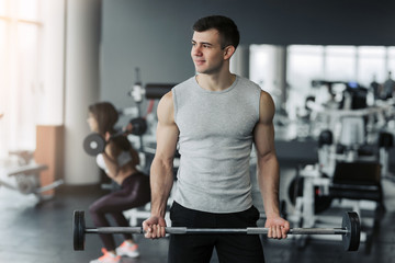 Handsome muscular man working out with dumbbells in the gym.