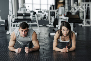 Young muscular couple doing doing hard workout at the gym. Doing plank in the gym. © JJ Studio