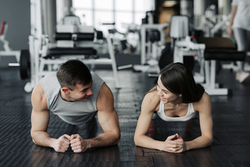 Young muscular couple doing doing hard workout at the gym. Doing plank in the gym. © JJ Studio