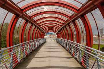 Red and steel walkways of a pedestrian foot bridge.