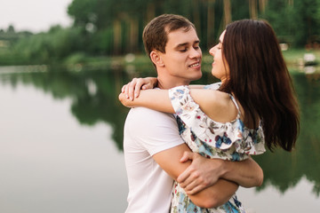 Young loving couple hugging near lake on sunset.