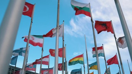 International flags of different countries waving in the wind on flagpoles - Ukrainian, Norway, Poland, Canadian, Georgian, Armenian, Lithuanian, Austrian and more