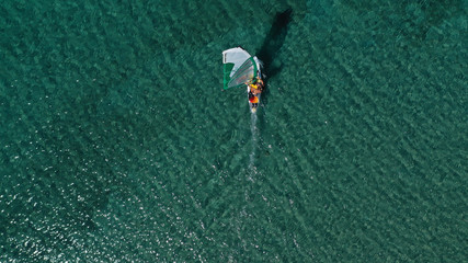 Fototapeta premium Aerial top view photo of fit man practising wind surfing in exotic open ocean bay with crystal clear emerald sea
