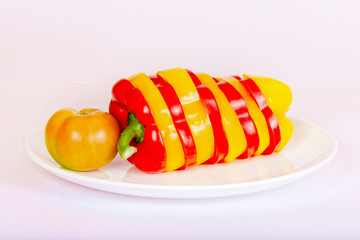Bulgarian pepper and tomatoes lie on a white plate.