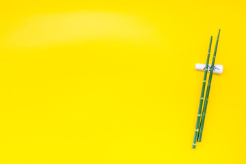 bamboo sticks for sushi and maki on yellow background top view mockup