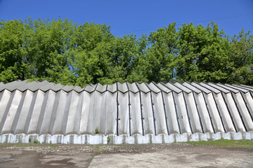 Industrial hangar with aluminum walls and roof stands on a concrete foundation near green trees
