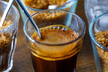coffee in glass cup with metal spoon and sugar