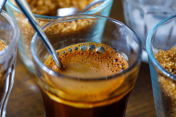 coffee in glass cup with metal spoon and sugar