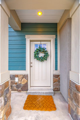 Facade of a home with a simple leafy wreath hanging on the white front door