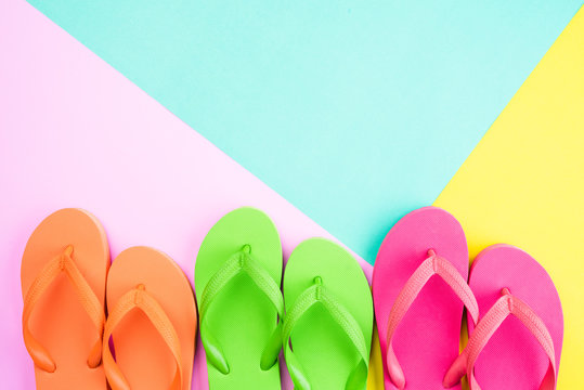Top view of colorful flip flop on pink and yellow background for summer holiday and vacation concept.