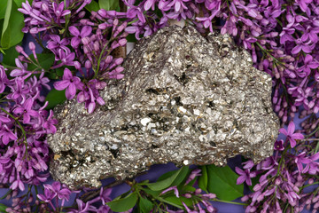 Natural Pyrite Cluster Specimen from Peru surrounded by purple lilac flowers.