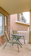 Clear Vertical Front porch of a home with table and chairs in front of brick wall and window