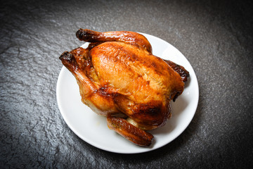 Roasted chicken - baked whole chicken grilled on white plate and dark background on top view