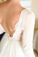 Fototapeta na wymiar Beautiful and slim bride's back with her dress on her wedding day