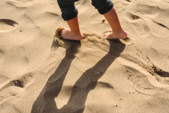 Feet of boy walking on the sand of the beach.
