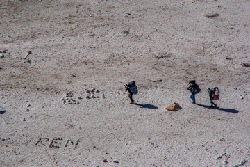 Landscape view of three sherpas carrying heavy bags. Sagarmatha (Everest) National Park, Nepal.