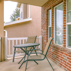 Fototapeta na wymiar Clear Square Front porch of a home with table and chairs in front of brick wall and window