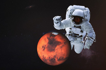 Fototapeta na wymiar Giant astronaut near Mars planet of Solar system. Science fiction wallpaper. Elements of the image are furnished by NASA