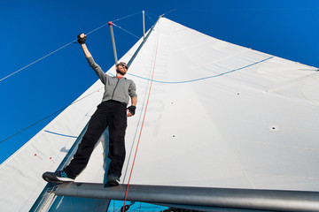 Obraz premium Young man lifting the sail of catamaran during cruising