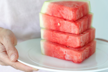 Hand holding ceramic white plate with watermelon slice concept. Watermelon is healthy fruit for summer and diet food