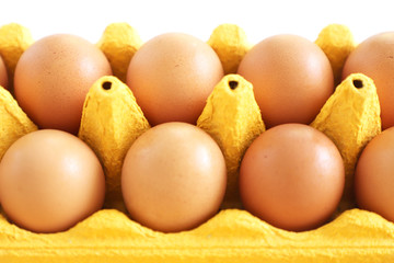 Chicken eggs in yellow carton box on white table. Close up