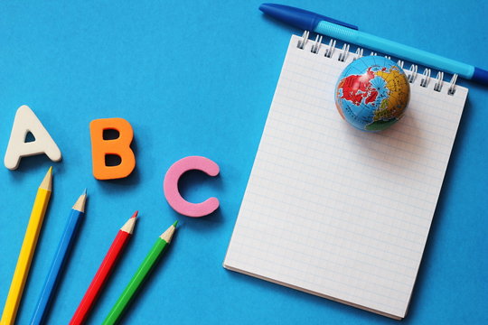 ABC-the First Letters Of The English Alphabet On A Blue Background. Notebook And Pen. Empty Space For Text. Learn Foreign Languages.