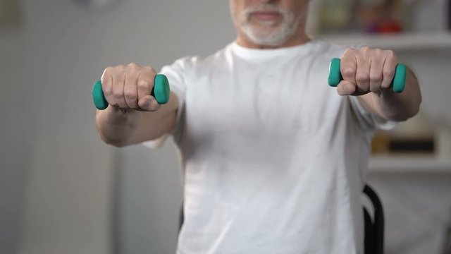 Old man lifting dumbbells, training muscles and joints after injury or insult