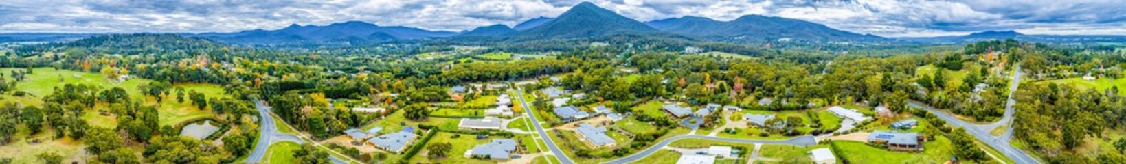 Wide aerial panorama of scenic countryside with houses surrounded by forest and mountains. Healesville, Victoria, Australia