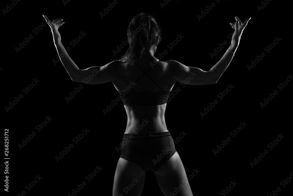 Wall mural Fit woman demonstrate perfect back and shoulders on black background