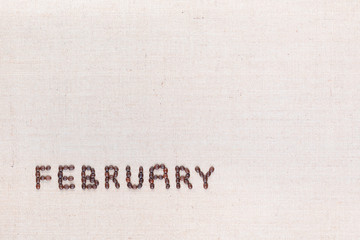 The word February written with coffee beans shot from above, aligned at the bottom left.