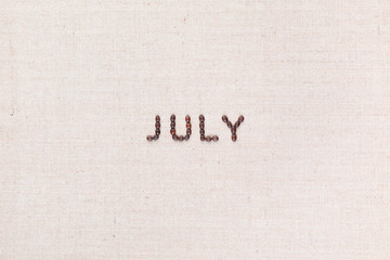 The word July written with coffee beans shot from above, aligned in the center.