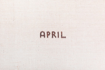 The word April written with coffee beans shot from above, aligned in the center.