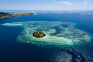 Seen from a bird's eye view, an idyllic island is surrounded by a healthy coral reef in Komodo National Park, Indonesia. This tropical area is known for its marine biodiversity as well as its dragons.