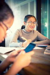 toothy smiling face of asian girl doing school home work in home living room