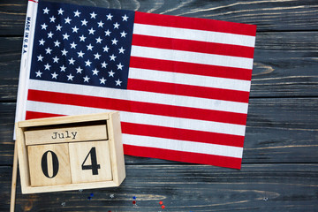 Obraz premium Wooden calendar 4th of July day of American independence, decorations, flag, candles, straws. USA holiday decorations on a wooden background, top view, flat lay
