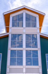 Large glass window of a building with a bright and cloudy blue sky background