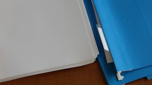 Hands are placing papers in a file folder .