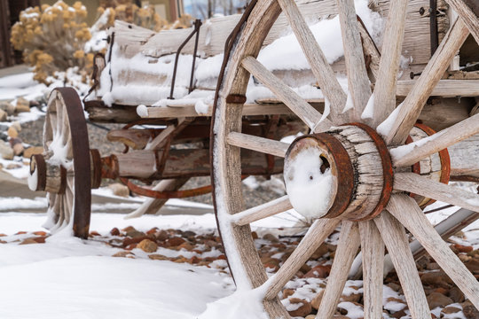 Close up of the rusty wheels of a weathered wooden wagon viewed in winter