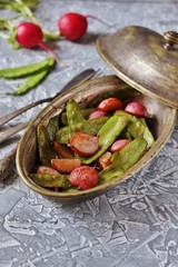 Fried young peas and radish pods. In the style of Provence. light background. Soft focus