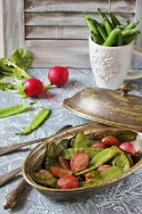 Fried young peas and radish pods. In the style of Provence. light background. Soft focus