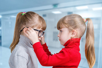 A child puts glasses on his twin sister .
