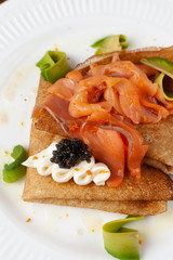 Russian traditional crepes with smoked salmon, black caviar, avocado and cream cheese for shrovetide