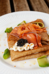 Russian traditional crepes with smoked salmon, black caviar, avocado and cream cheese for shrovetide