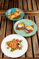 Different kinds of thin pancakes or blini with pineapple and caramel sauce, smoked salmon and caviar, poached egg and bacon