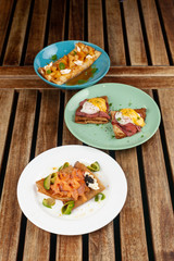 Different kinds of thin pancakes or blini with pineapple and caramel sauce, smoked salmon and caviar, poached egg and bacon